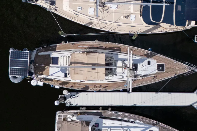 Slide: The Image of Aerial view of 1991 Oyster LW48 yacht docked, featuring solar panels and wooden deck. - 52