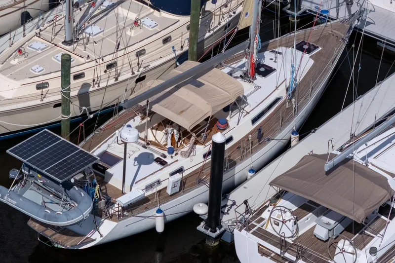Slide: The Image of Sailboats docked at marina, featuring a 1991 Oyster LW48 with solar panel. - 53