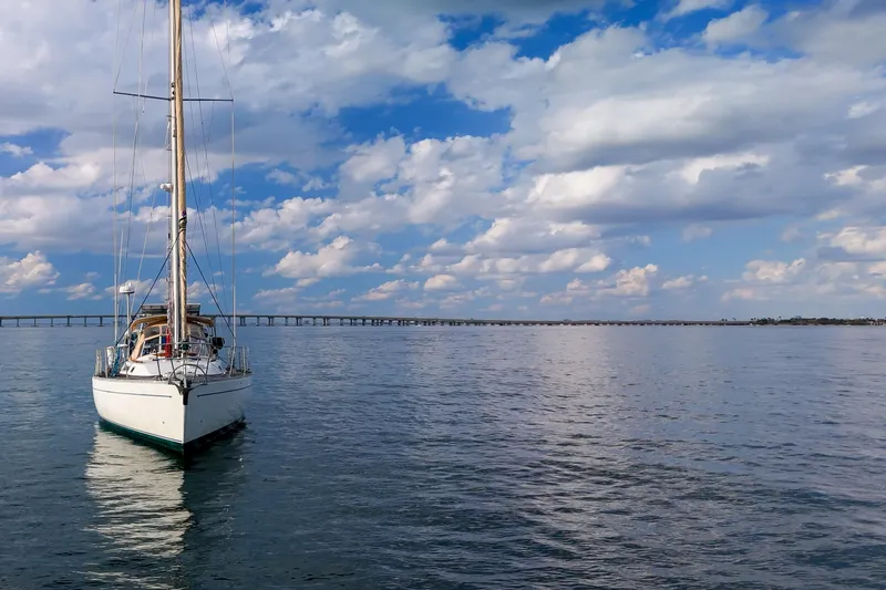 Slide: The Image of Sailboat Oyster Lightwave 48 (1991) on calm water under a partly cloudy sky. - 75