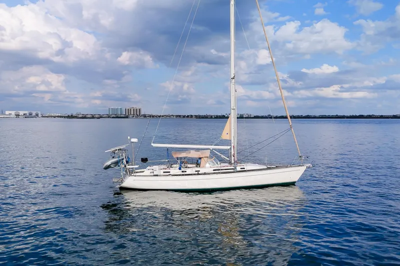 Slide: The Image of Sailboat Oyster Lightwave 48, 1991 model, on calm water under a partly cloudy sky. - 77