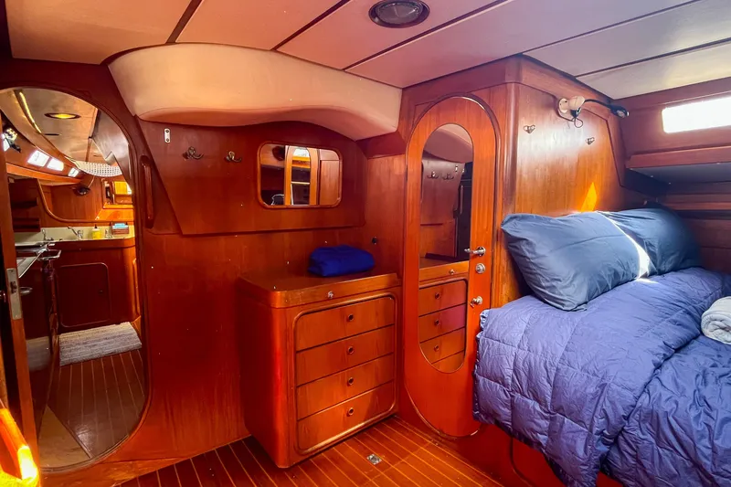 Slide: The Image of Luxurious 1991 Oyster LW48 yacht interior with wooden cabinetry and cozy bedding. - 9