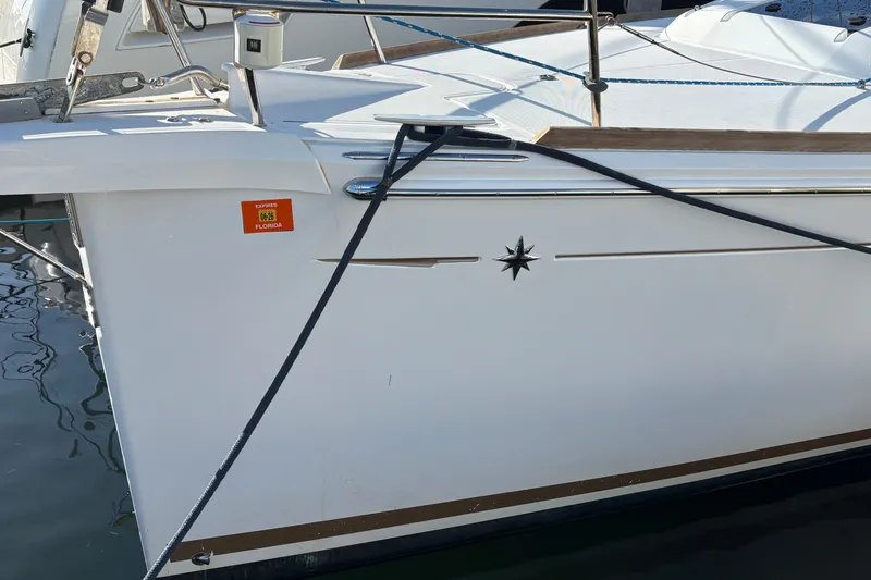 Slide: The Image of 2018 Jeanneau Sun Odyssey 389 sailboat docked, featuring sleek design and nautical emblem. - 2