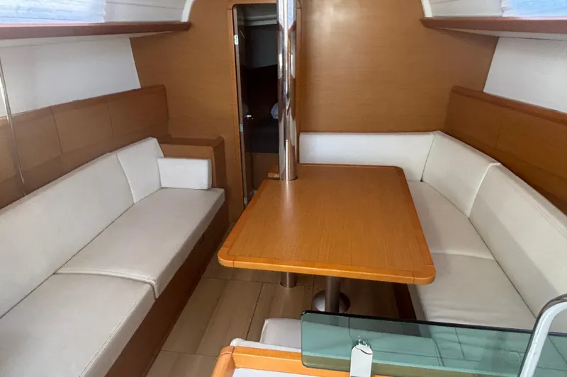 Slide: The Image of Interior of 2018 Jeanneau Sun Odyssey 389 sailboat with wooden table and white seating. - 3