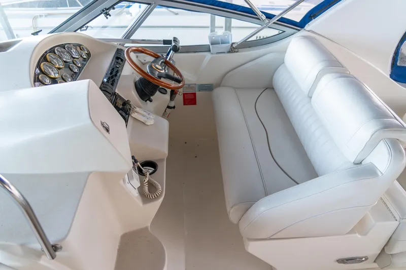 Slide: The Image of 2000 Cruisers Yachts 3375 Express helm with white seating and wooden steering wheel. - 17