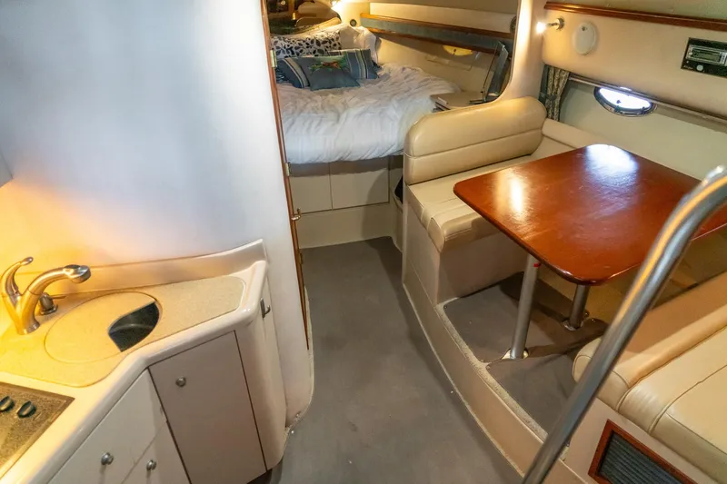 Slide: The Image of 2000 Cruisers Yachts 3375 Express interior with kitchenette, dining area, and cozy sleeping quarters. - 21