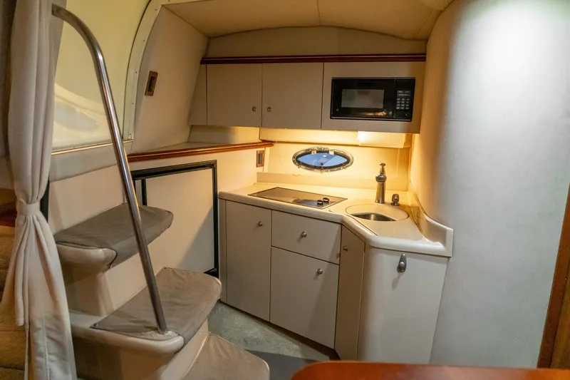 Slide: The Image of 2000 Cruisers Yachts 3375 Express interior kitchen with microwave, sink, and stairs. - 27