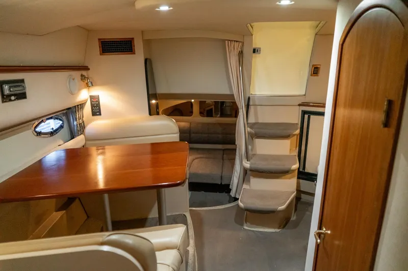 Slide: The Image of Interior of 2000 Cruisers Yachts 3375 Express, featuring cozy seating and wooden table. - 30