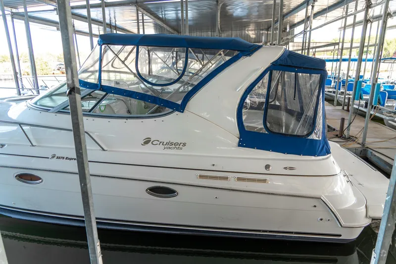 Slide: The Image of 2000 Cruisers Yachts 3375 Express docked, featuring blue canopy and sleek design. - 4