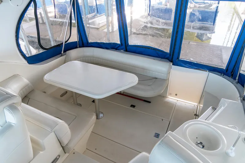 Slide: The Image of 2000 Cruisers Yachts 3375 Express interior with white seating, table, and blue canopy. - 18
