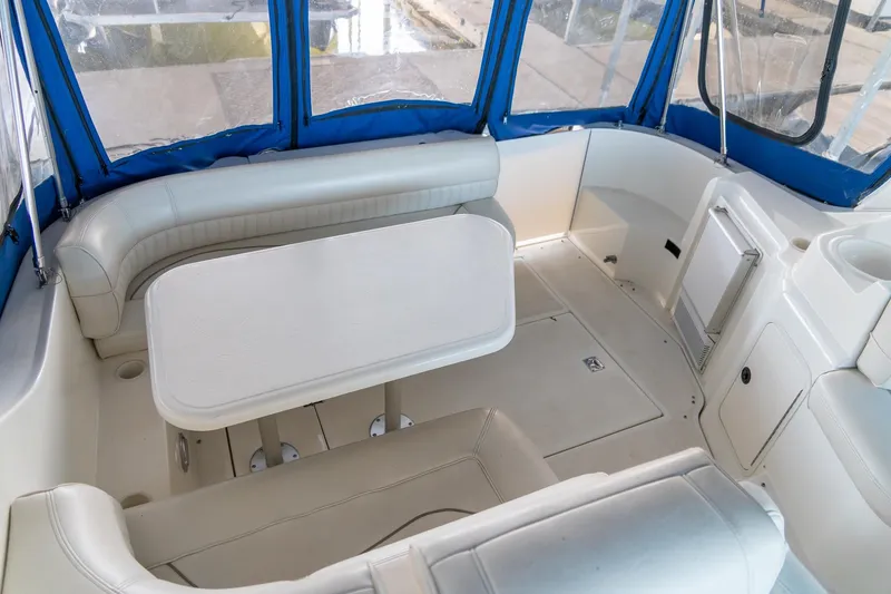 Slide: The Image of 2000 Cruisers Yachts 3375 Express interior with white seating and table, blue canopy. - 19