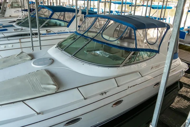 Slide: The Image of 2000 Cruisers Yachts 3375 Express docked, featuring sleek design and blue canopy. - 3