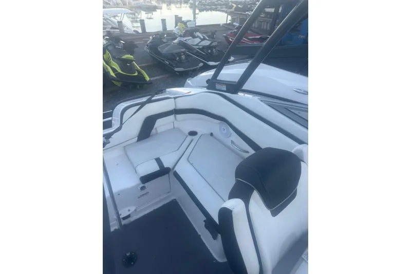 Slide: The Image of 2015 Yamaha Boats AR240 HO interior with white and black seating at a marina. - 7