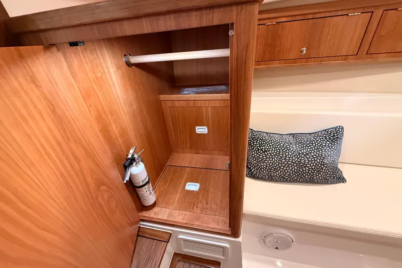 Slide: The Image of Wooden interior of 2026 MJM 38R boat with storage, fire extinguisher, and cushion. - 32