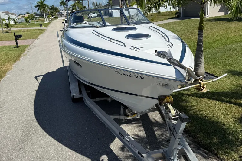 Slide: The Image of 1999 Cobalt 293 boat parked on a sunny residential street with palm trees. - 10