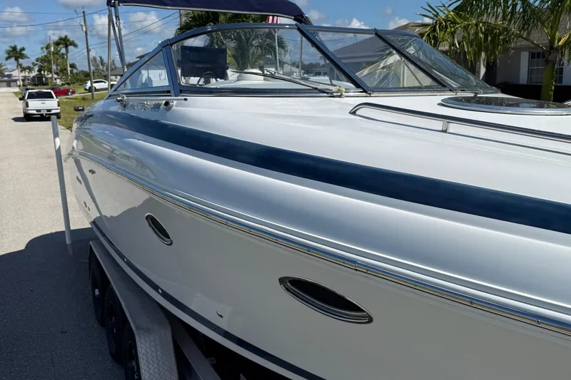 Slide: The Image of 1999 Cobalt 293 boat parked on a sunny street with palm trees. - 11