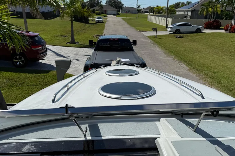 Slide: The Image of 1999 Cobalt 293 boat interior with white and beige seating, near grass and pavement. - 18
