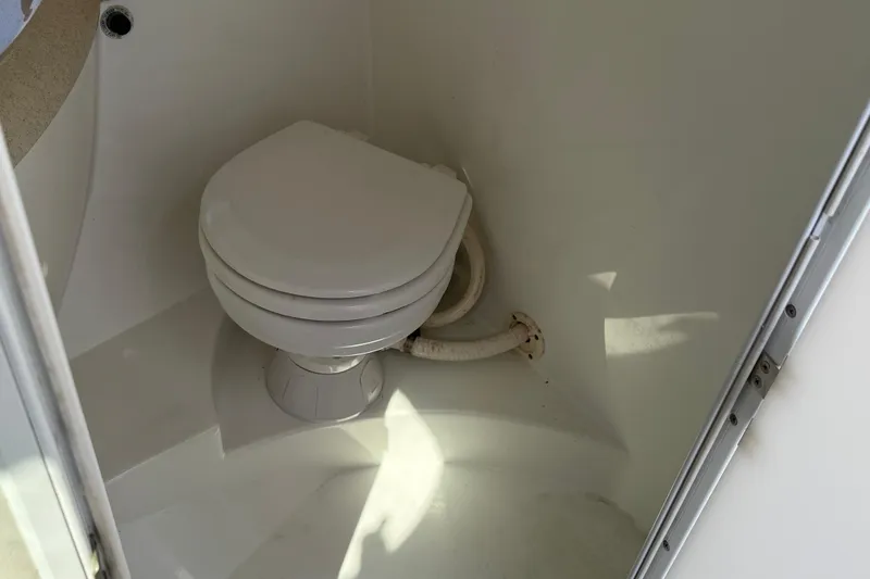 Slide: The Image of Compact bathroom in a 1999 Cobalt 293 boat, featuring a toilet and sink. - 42