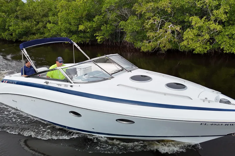 Slide: The Image of 1999 Cobalt 293 boat cruising on a river with lush greenery in the background. - 76