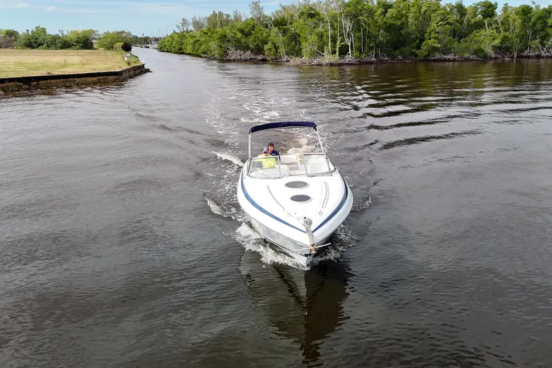 Slide: The Image of 1999 Cobalt 293 boat cruising on a calm river near lush greenery. - 80
