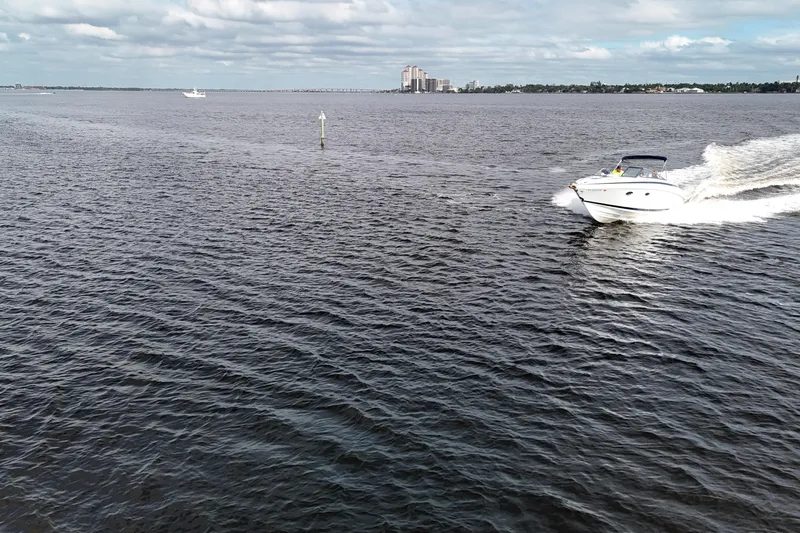 Slide: The Image of A 1999 Cobalt 293 boat cruising on open water under a cloudy sky. - 82