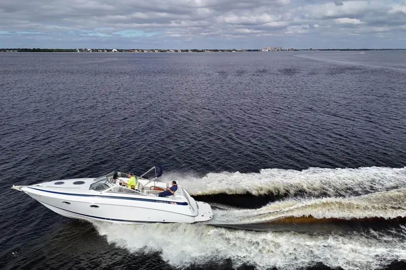 Slide: The Image of A 1999 Cobalt 293 boat cruising on a vast, calm water body under a cloudy sky. - 83