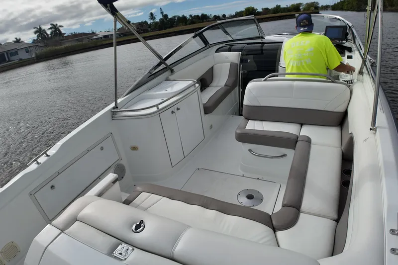 Slide: The Image of 1999 Cobalt 293 boat interior with white seating and a person steering on a river. - 86