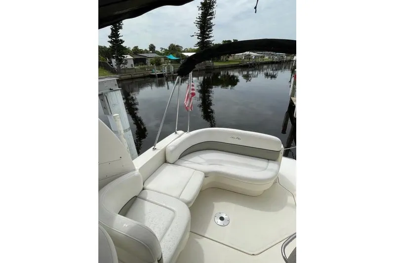 Slide: The Image of 2006 Sea Ray 260 Sundancer boat with white seating, docked by a calm waterfront. - 13