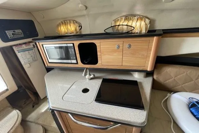 Slide: The Image of 2006 Sea Ray 260 Sundancer cabin kitchen with microwave, sink, and stove. - 17