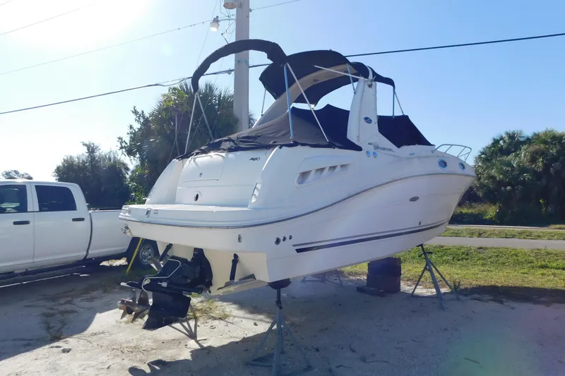 Slide: The Image of 2006 Sea Ray 260 Sundancer boat on stands, parked beside a white truck. - 5