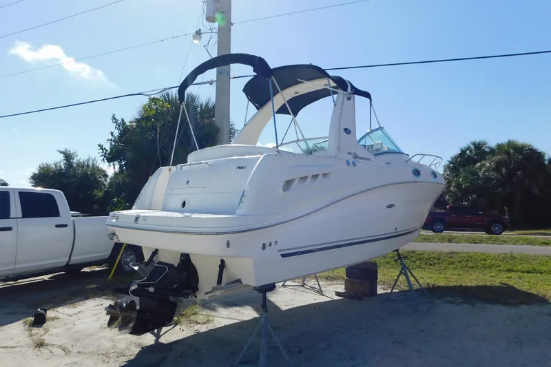 Slide: The Image of 2006 Sea Ray 260 Sundancer boat on stands, parked beside a white truck. - 6