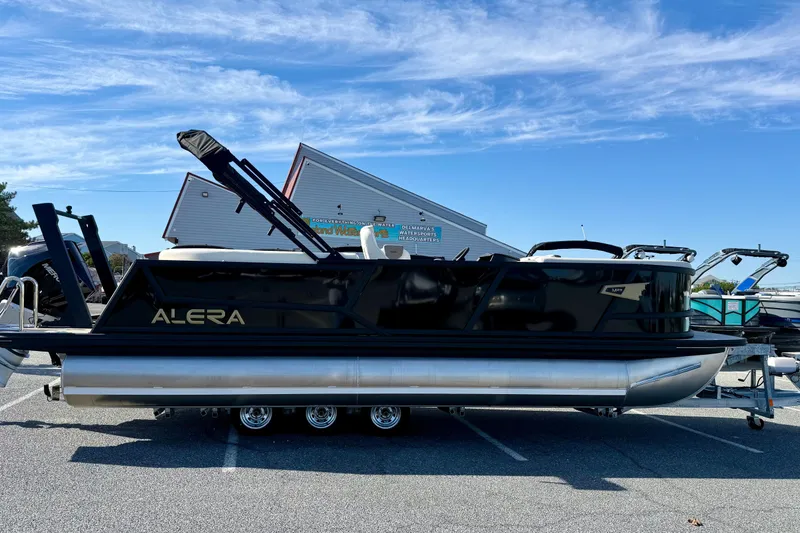 The Image of 2026 Alera M23 pontoon boat parked outdoors under a clear blue sky. - 0