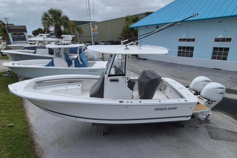 Slide: The Image of 2026 Regulator 23 boat with twin Yamaha engines, displayed outdoors near a blue building. - 13