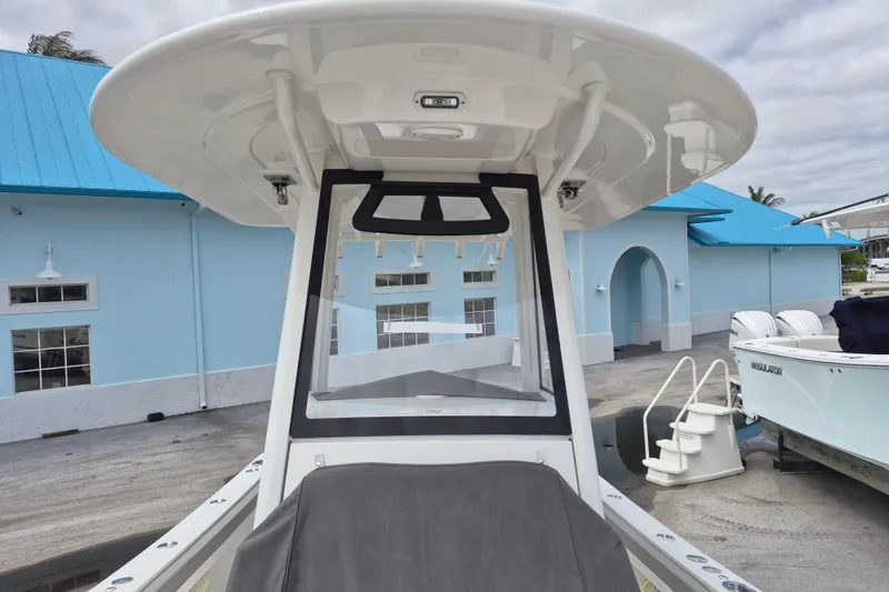 Slide: The Image of 2026 Regulator 23 boat with T-top, docked near blue building. - 16