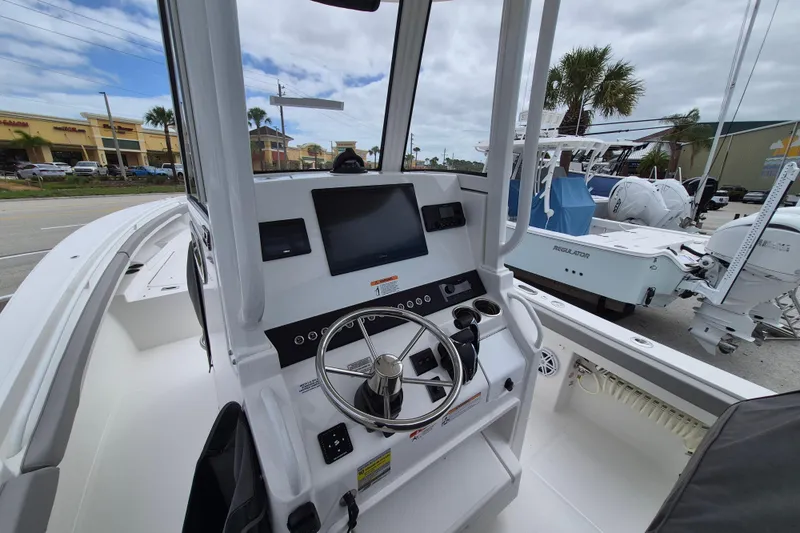 Slide: The Image of 2026 Regulator 23 boat cockpit with steering wheel and modern controls, parked outdoors. - 17