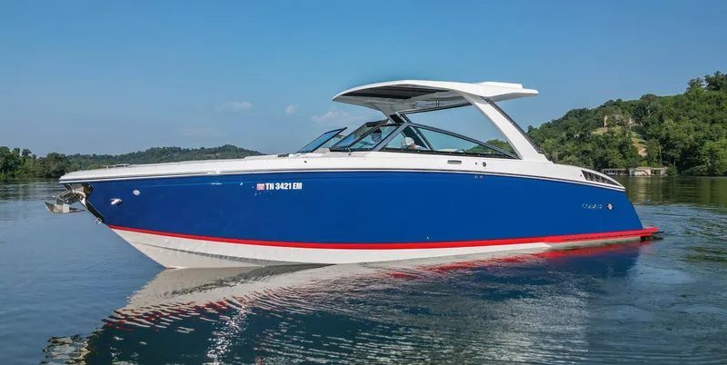 Slide: The Image of 2023 Cobalt R33 boat in blue on a calm lake with lush green background. - 11