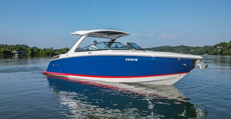 Slide: The Image of 2023 Cobalt R33 boat cruising on a serene lake under a clear blue sky. - 14