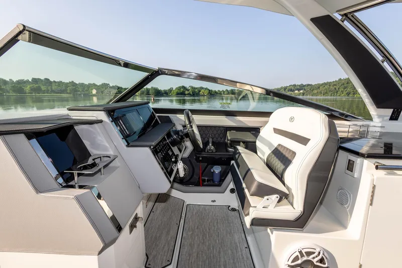 Slide: The Image of 2023 Cobalt R33 boat cockpit with modern controls and luxurious seating on a serene lake. - 16