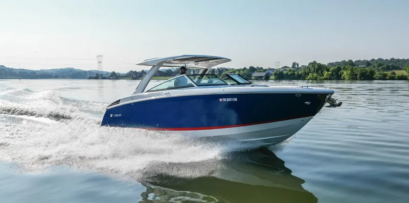 Slide: The Image of 2023 Cobalt R33 boat cruising on a calm lake with scenic background. - 5