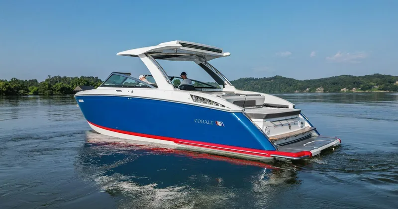 Slide: The Image of 2023 Cobalt R33 boat cruising on a serene lake with lush green hills. - 8