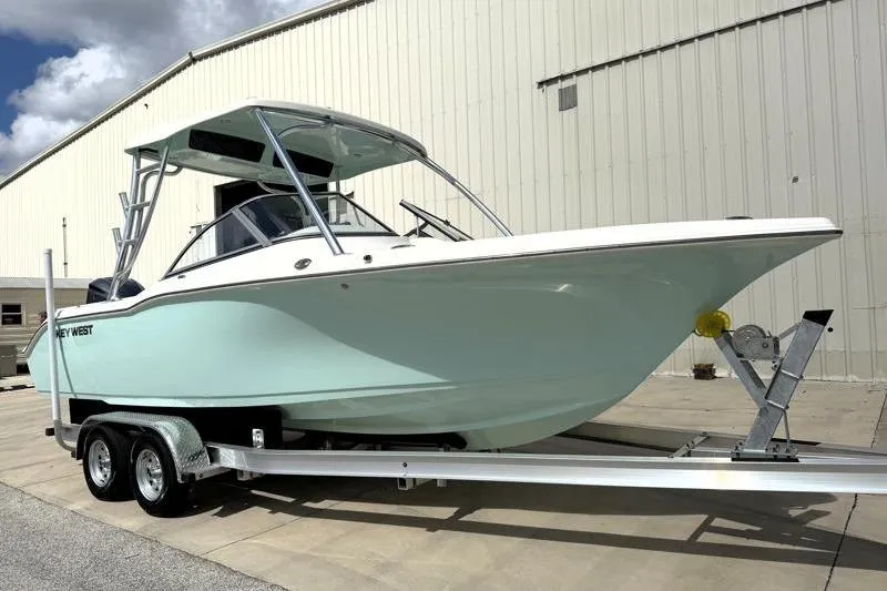 Slide: The Image of 2024 Key West 239 DFS boat on trailer, parked outside a warehouse. - 1