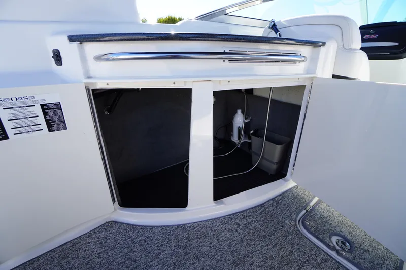 Slide: The Image of 2014 Chaparral 287 SSX boat storage compartment with open doors and visible interior. - 34
