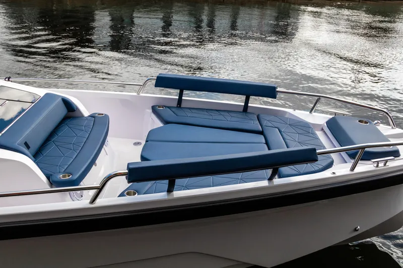 Slide: The Image of 2026 Axopar 29 Sun Top boat with blue cushioned seating on calm water. - 8