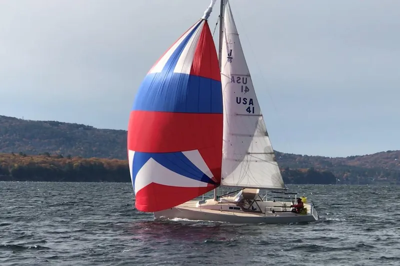 Slide: The Image of 2016 J Boats J 95 sailboat docked on a serene lake with autumn trees. - 2