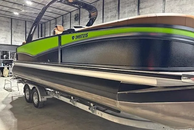 The Image of 2025 Premier 250 Solaris RF pontoon boat with green and black design in a warehouse. - 1