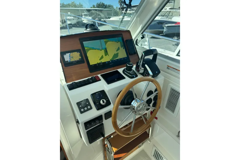 Slide: The Image of 2024 Back Cove 34O boat cruising on a calm river under a partly cloudy sky. - 16