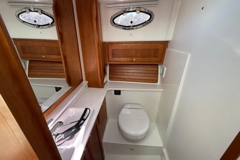 Slide: The Image of 2024 Back Cove 34O yacht kitchen with stove, microwave, and wooden cabinetry. - 27