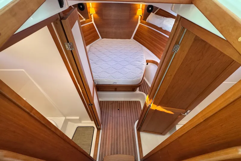 Slide: The Image of 2024 Back Cove 34O cabin interior with wood finish and cozy bed. - 45