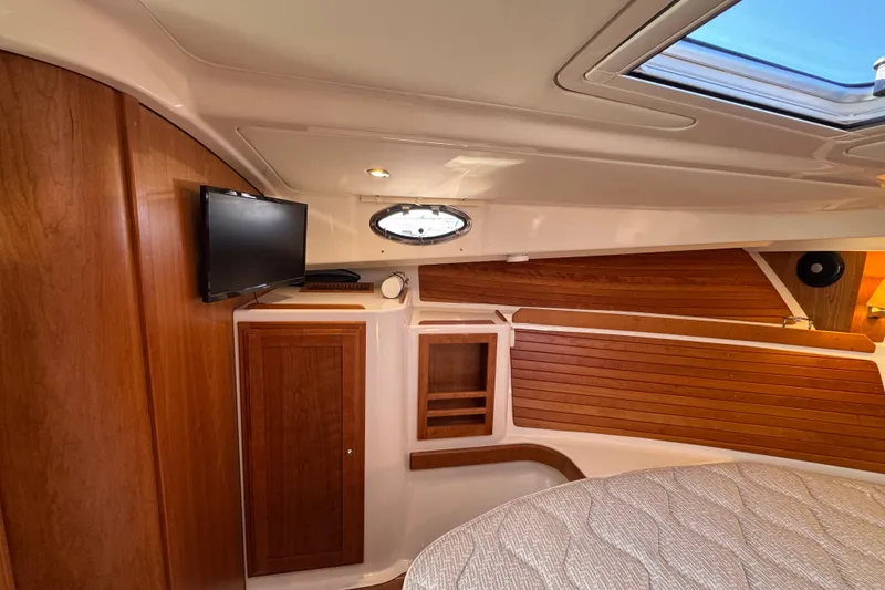 Slide: The Image of 2024 Back Cove 34O cabin interior with wood paneling and mounted TV. - 53