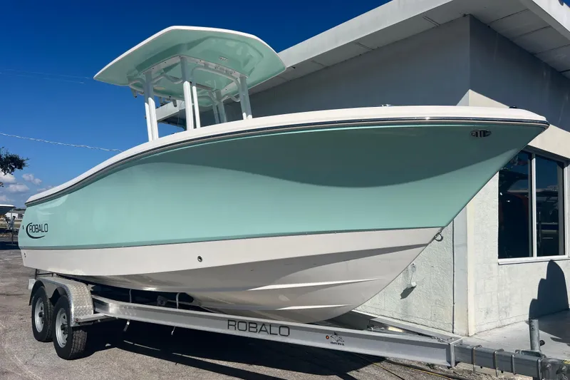 The Image of 2024 Robalo R232 Explorer boat on trailer, light blue hull, parked outdoors. - 0