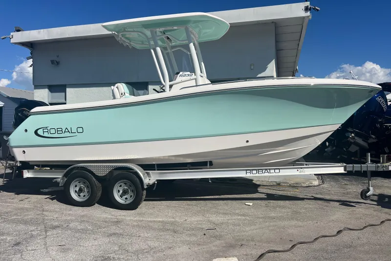 Slide: The Image of 2024 Robalo R232 Explorer boat on trailer, light blue and white design. - 2